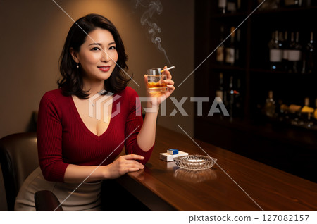 Woman drinking whiskey and smoking a cigarette at a bar 127082157
