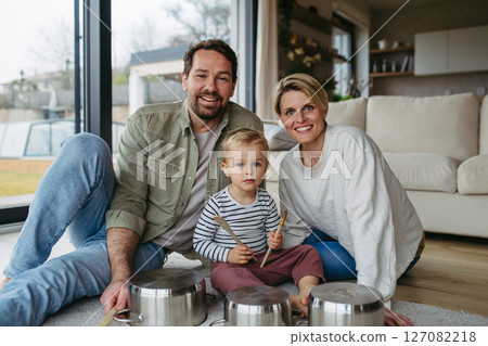 Parents and toddler son playing drums on kitchen pots 127082218