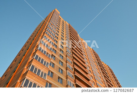 multi-storey new yellow brick house against the blue sky. Mortgage, real estate, new housing, copy space. 127082687