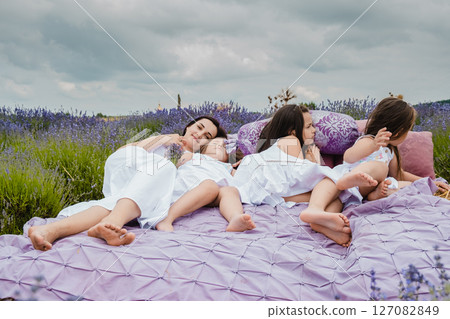 A young mother and her three lovely daughters lie on a large straw bed in the middle of a lavender field A young mother and her three lovely daughters lie on a large straw bed in the middle of a lavender field 127082849