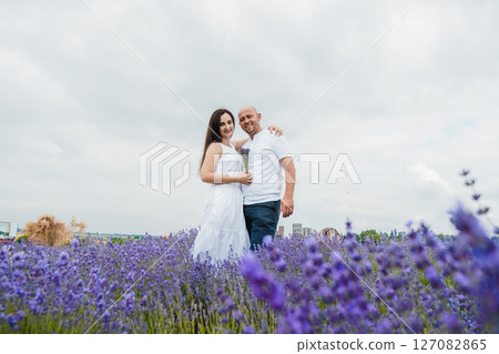 The lavender field envelops the lovers with a delicate scent, they stand in each other's arms The lavender field envelops the lovers with a delicate scent, they stand in each other's arms 127082865