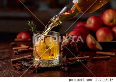 Apple kombucha is poured from a bottle into a crystal glass. Apple kombucha is poured from a bottle into a crystal glass. 127083016