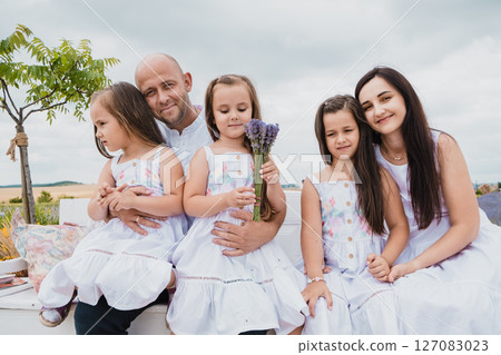 A happy mother and father gently embrace their daughters 127083023
