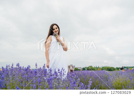 A young woman in a white dress stands in the lavender field 127083029