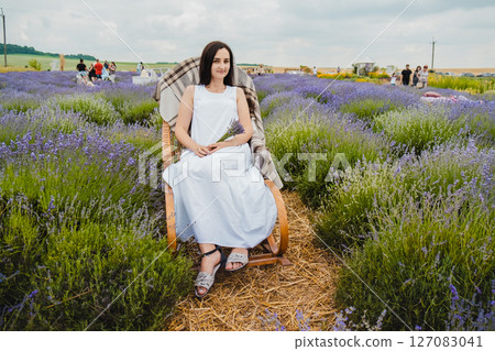 Among the purple lavender field, a young woman relaxes on a rocking chair Among the purple lavender field, a young woman relaxes on a rocking chair 127083041