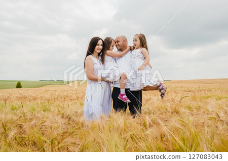 The young family is spending time among the yellow ears of barley The young family is spending time among the yellow ears of barley 127083043