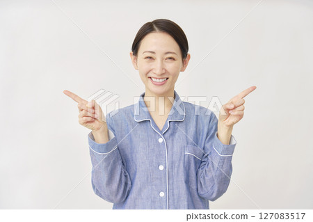 Woman in pajamas pointing left and right on white background 127083517