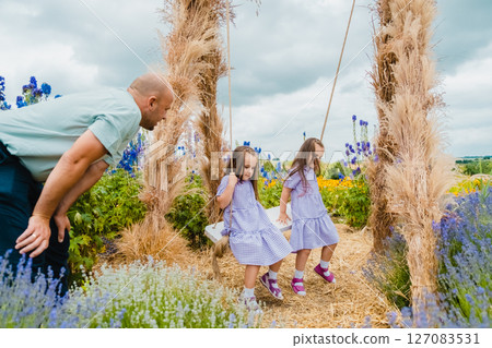 A young father and his daughters enjoy time together on a beautiful swing 127083531