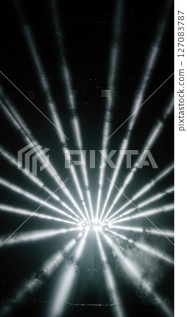Powerful geometric light beam patterns cutting through artificial fog creating volumetric illumination at dark music venue Powerful geometric light beam patterns cutting through artificial fog creating volumetric illumination at dark music venue 127083787