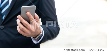 Close up hand businessman using smart phone to work with financial data in city 127084357