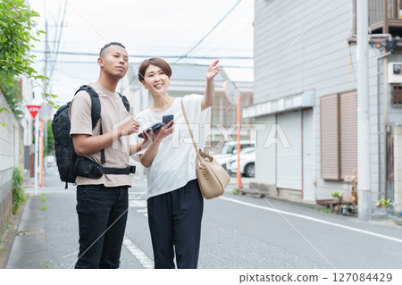 A woman giving directions to a foreigner using a smartphone translation app A woman giving directions to a foreigner using a smartphone translation app 127084429
