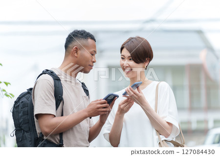A woman giving directions to a foreigner using a smartphone translation app 127084430