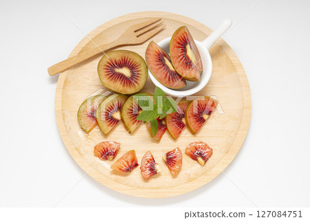 Ruby Red Kiwifruit cut into pieces and served on a wooden plate 127084751
