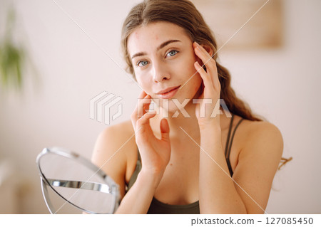 Woman worry about her face when she saw the problem of acne occur by a mini mirror. Pimples, acne 127085450