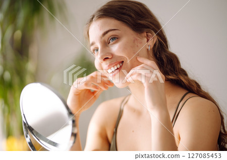 Woman worry about her face when she saw the problem of acne occur by a mini mirror. Pimples, acne 127085453