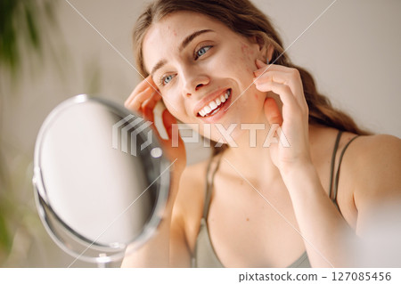 Woman worry about her face when she saw the problem of acne occur by a mini mirror. Pimples, acne 127085456