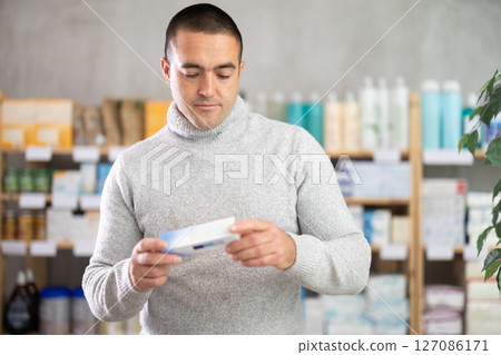 Man choose antifungal ointment in pharmacy Man choose antifungal ointment in pharmacy 127086171