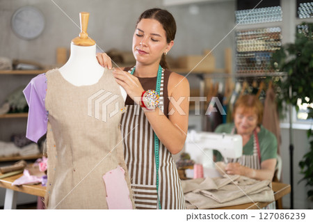 Woman working with mannequin against the background of an elderly dressmaker 127086239