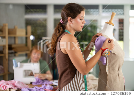Young woman working with mannequin, elderly woman sewing 127086399