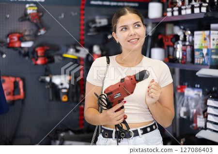 Woman buys electric drill, collect necessary supplies in store according to list for apartment repairs 127086403