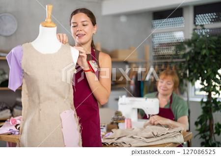 Woman working with mannequin against the background of an elderly dressmaker 127086525