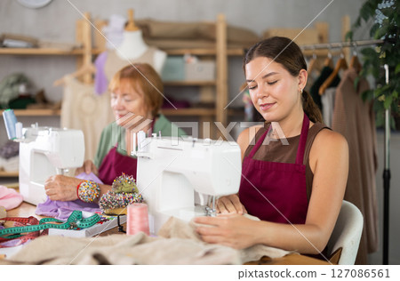 Seamstresses work on machines in a sewing workshop 127086561