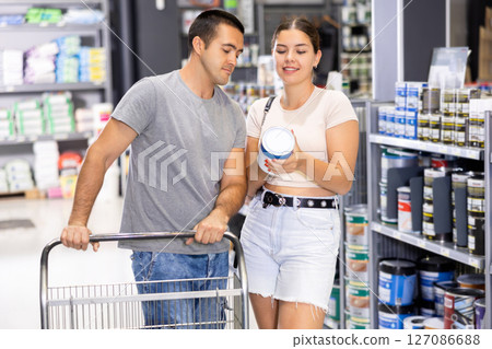 Husband and wife choose a can of paint together at hardware store 127086688