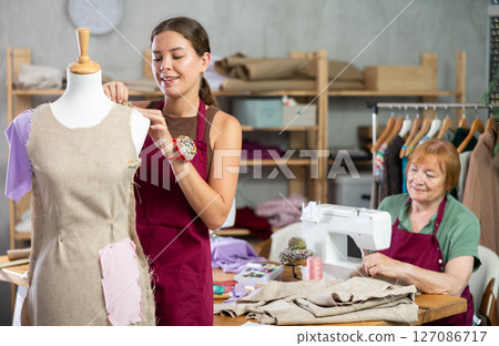 Woman working with mannequin against the background of an elderly dressmaker 127086717