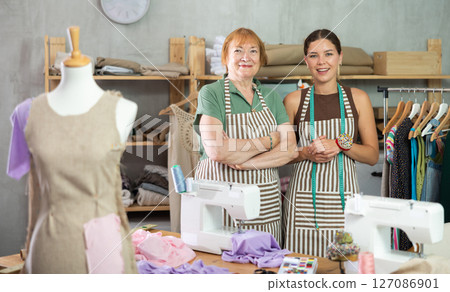 Female dressmakers standing in the workshop near the table Female dressmakers standing in the workshop near the table 127086901