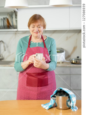 Smiling mature woman writes a message to someone on a mobile 127086939