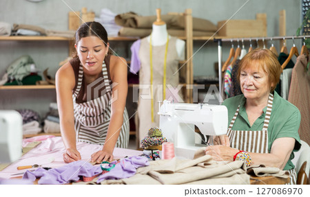 woman dressmaker makes markings on the fabric next to the seamstress 127086970