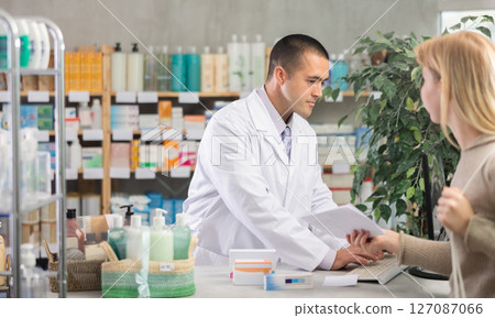 Young male pharmacist serving girl holding prescription in drugstore Young male pharmacist serving girl holding prescription in drugstore 127087066