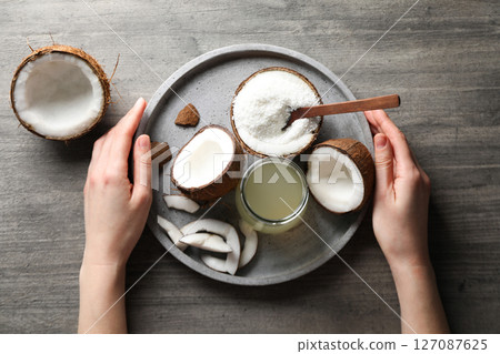 Coconut milk in a jug on a gray background, with coconut fruits. 127087625