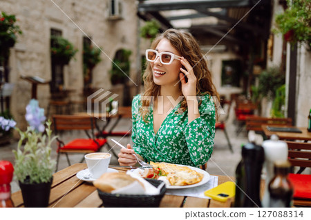Portrait of a smiling woman eating pasta at cozy Italian restaurant outdoors. Portrait of a smiling woman eating pasta at cozy Italian restaurant outdoors. 127088314