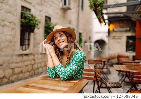 Young woman sitting by table of outdoor sidewalk cafe restaurant. People, fashion, lifestyle Young woman sitting by table of outdoor sidewalk cafe restaurant. People, fashion, lifestyle 127088349