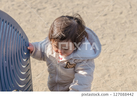 [A one-year-old child playing on a trampoline in the children's playground at Sagamihara City Asamizo Park] 127088442