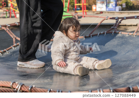 [相模原市麻溝公園兒童遊樂場，一歲小孩和媽媽在彈跳床上玩耍] 127088449