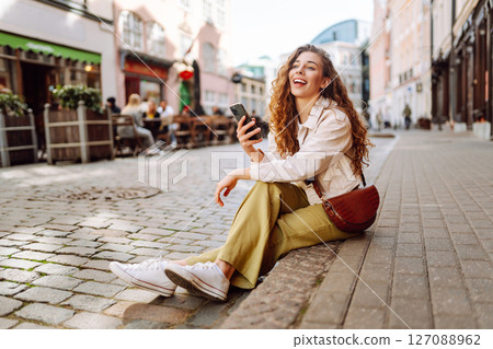 Happy woman using phone walking in city street. Lifestyle, travel, tourism, technology, blogging 127088962