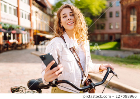 Young woman using mobile phone while riding bicycle at the city street outdoor. Selfie time. 127088966