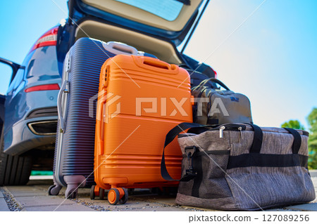Suitcases and bags in front of open car trunk, standing on pavement near suburban house. Luggage ready for loading in vehicle before travel or moving. Concept of relocation or road trip Suitcases and bags in front of open car trunk, standing on pavement near suburban house. Luggage ready for loading in vehicle before travel or moving. Concept of relocation or road trip 127089256