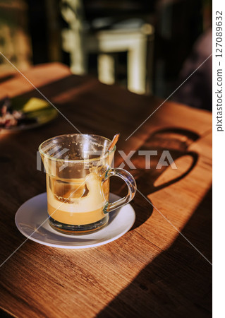 Calm morning. Still life of empty coffee cup. Empty glass coffee cup with milk foam remnants sits in sunlight on wooden cafe table, casting a soft shadow. Concept of coffee break, cozy moment Calm morning. Still life of empty coffee cup. Empty glass coffee cup with milk foam remnants sits in sunlight on wooden cafe table, casting a soft shadow. Concept of coffee break, cozy moment 127089632