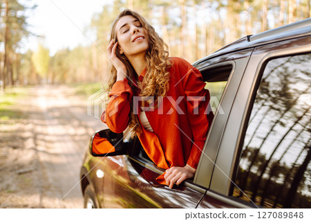 Young woman leaning out of the car window enjoying nature. Road trips summer holidays. Young woman leaning out of the car window enjoying nature. Road trips summer holidays. 127089848
