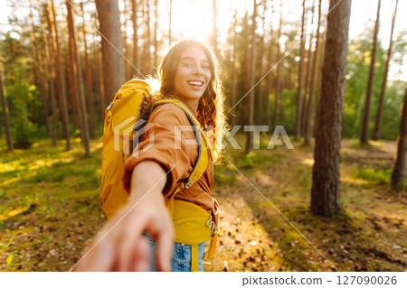 Traveling together. Happy woman holds the boyfriend's hand and walking on the forest. Vacation 127090026