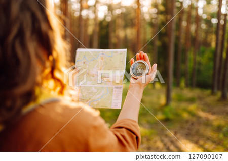 Traveler young woman searching direction with a compass on background of map in the forest. 127090107
