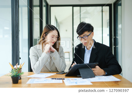 Two business people discuss financial strategy and collaborate with colleagues. 127090397