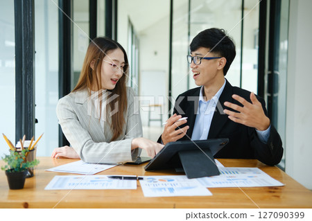 Two business people discuss financial strategy and collaborate with colleagues. Two business people discuss financial strategy and collaborate with colleagues. 127090399