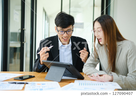Two business people discuss financial strategy and collaborate with colleagues. Two business people discuss financial strategy and collaborate with colleagues. 127090407