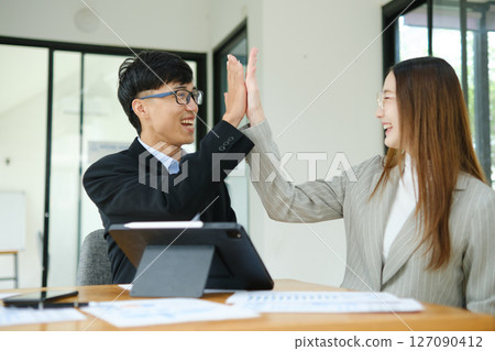 Two business people discuss financial strategy and collaborate with colleagues. 127090412