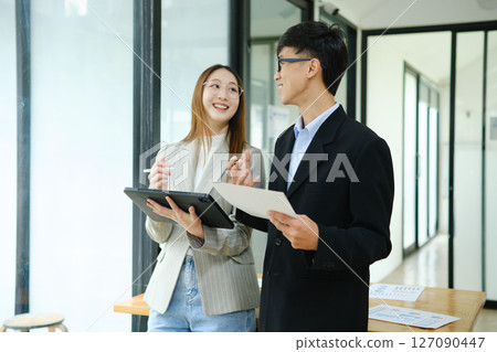 Two business people discuss financial strategy and collaborate with colleagues. 127090447