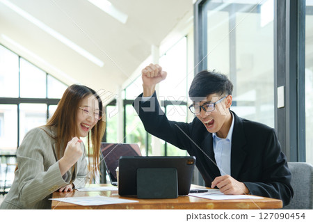 Two business people discuss financial strategy and collaborate with colleagues. 127090454